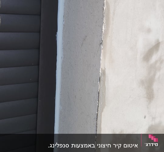 קיר בטון עם חריץ ליד תריס כהה